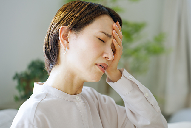 頭痛で額に手をあてる女性