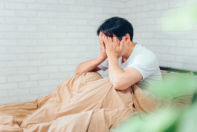 頭痛で頭を押さえる男性