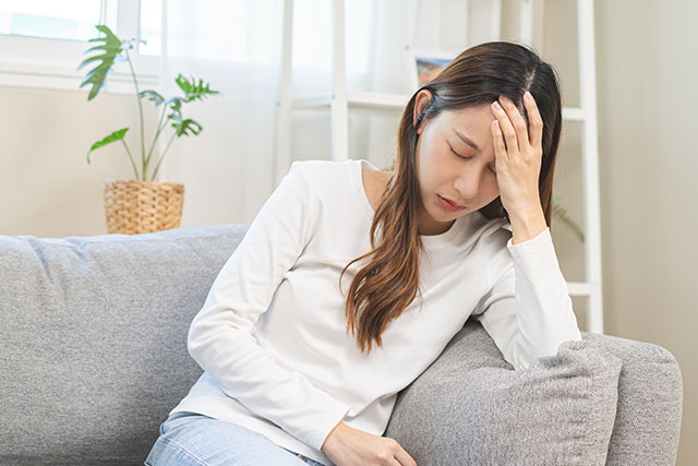 頭痛で額に手をあてる女性